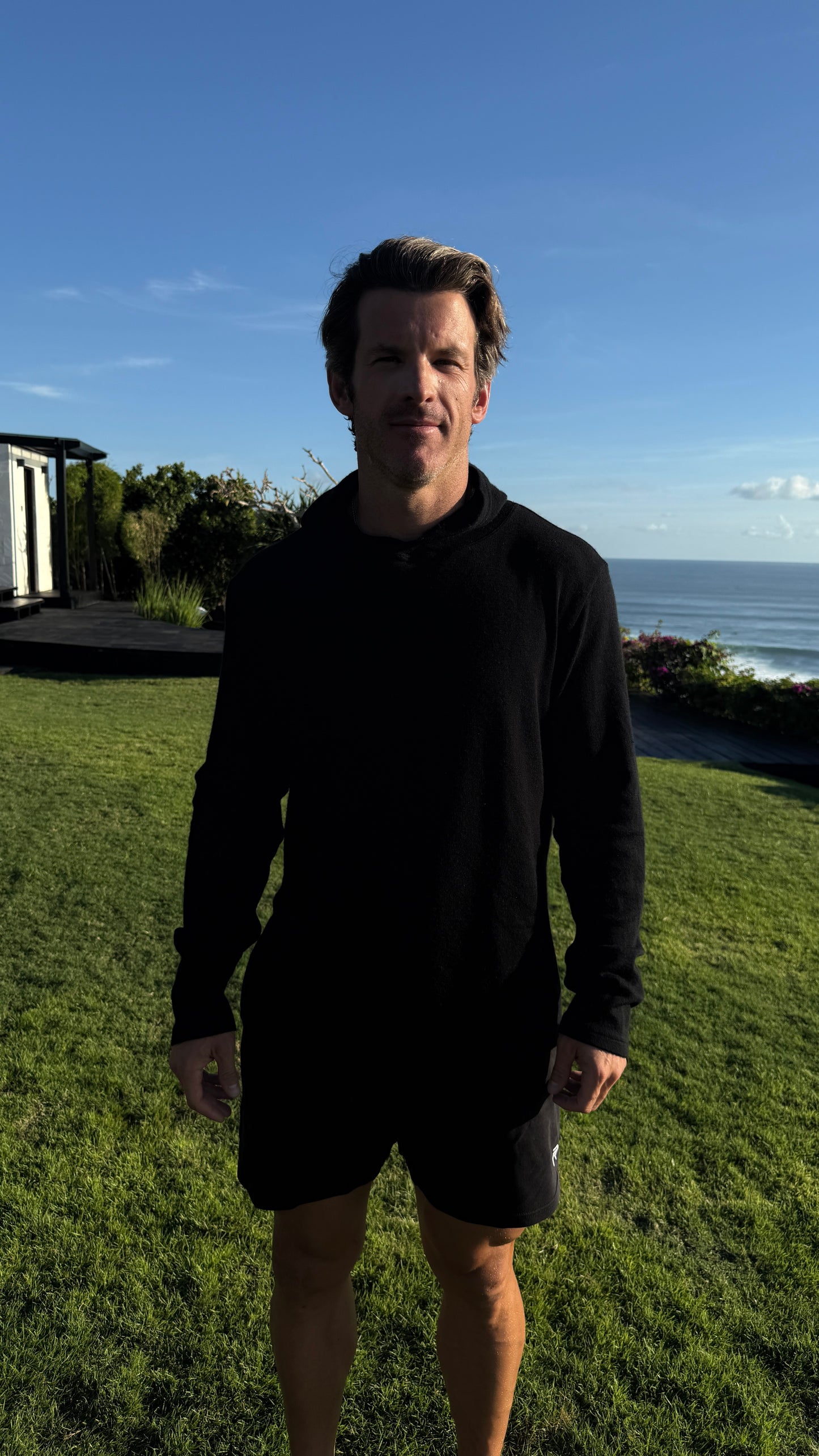 Man standing on grass with ocean and sky in the background