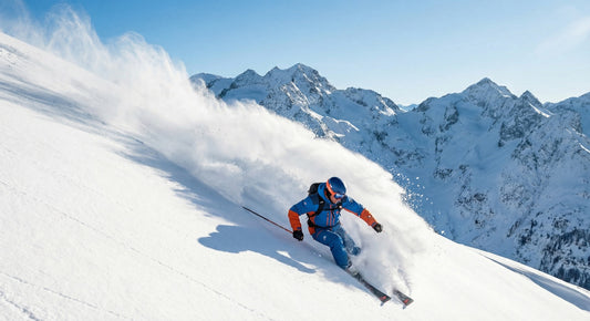 Skier carving powder turn on mountain slope with alpine peaks in background