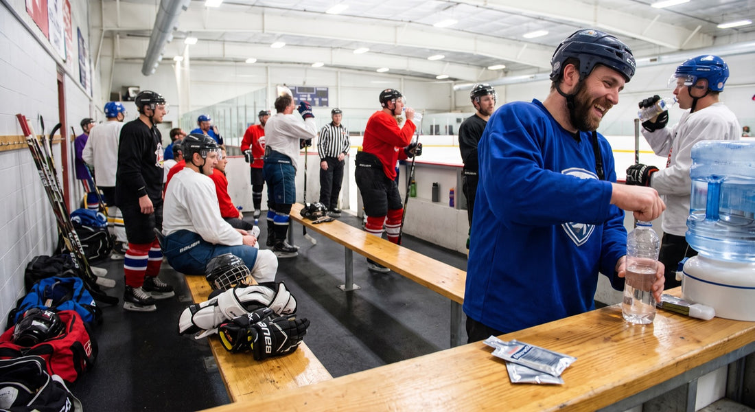 Adult hockey players preparing hydration bottles between tournament games