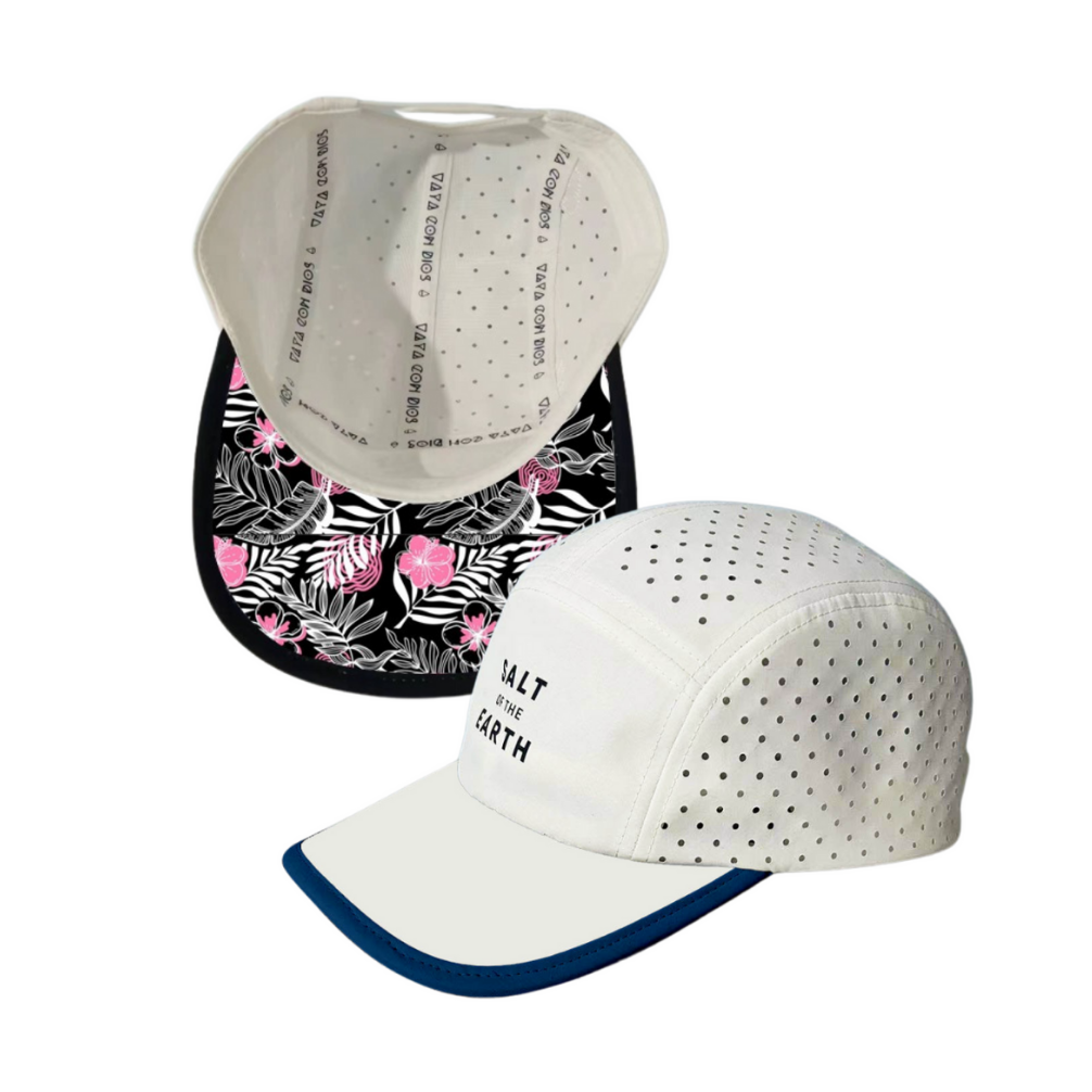 A white performance hat with black trim and a floral print on the inside, featuring perforations and an adjustable strap.